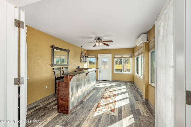 sunroom with ceiling fan and a wall mounted air conditioner