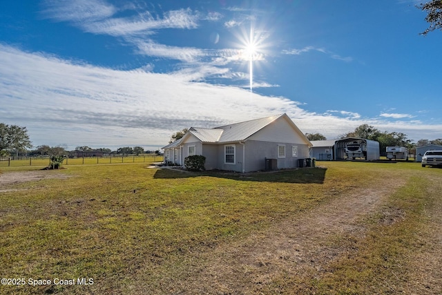 view of property exterior with central AC and a yard