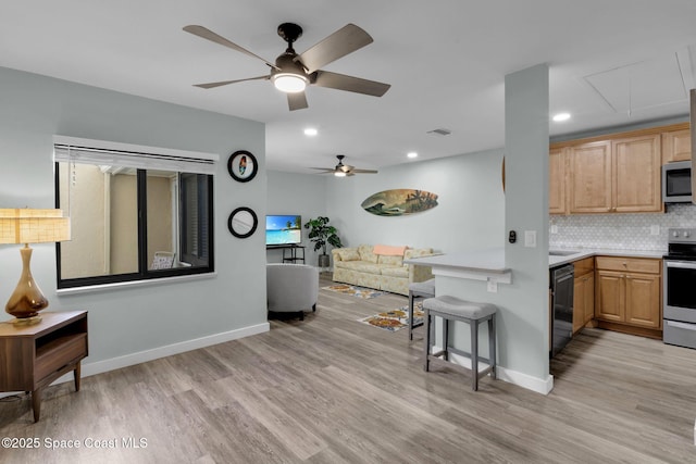 kitchen featuring ceiling fan, decorative backsplash, light hardwood / wood-style flooring, light brown cabinets, and stainless steel appliances