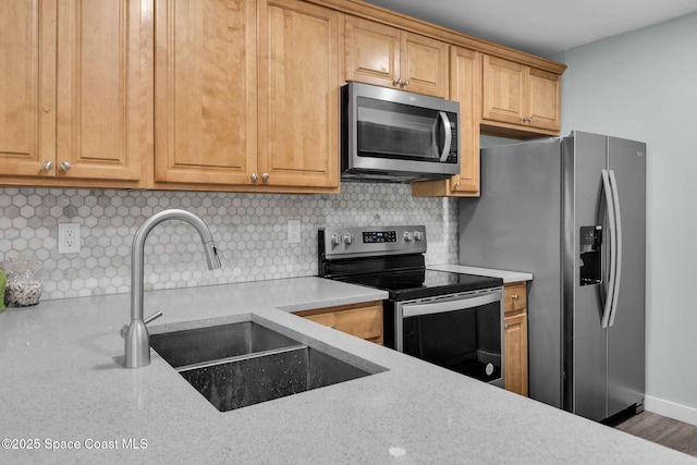 kitchen with stainless steel appliances, light stone countertops, sink, and decorative backsplash