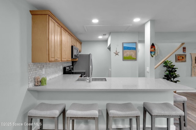 kitchen with stainless steel appliances, decorative backsplash, a kitchen bar, and kitchen peninsula