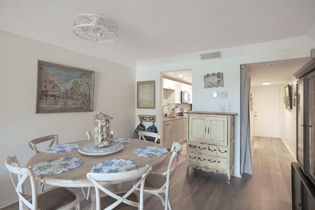 dining area featuring sink, a textured ceiling, and hardwood / wood-style flooring