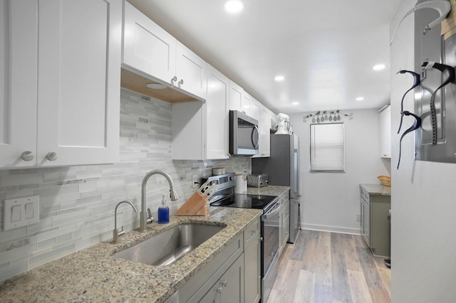 kitchen with white cabinets, sink, light stone counters, and stainless steel appliances