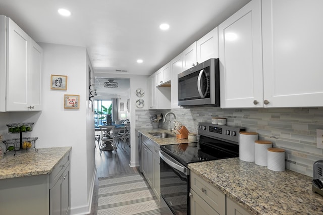 kitchen with white cabinetry, stainless steel appliances, backsplash, light stone countertops, and sink