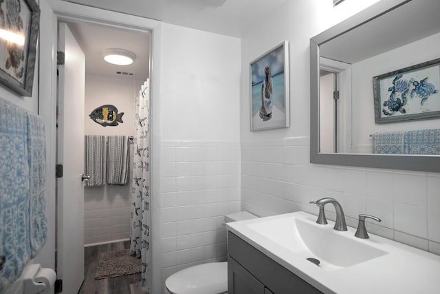 bathroom featuring toilet, tile walls, wood-type flooring, and vanity