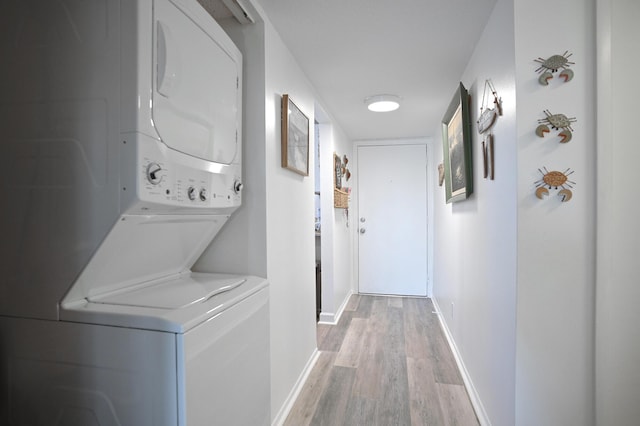 laundry room with light hardwood / wood-style floors and stacked washer and clothes dryer