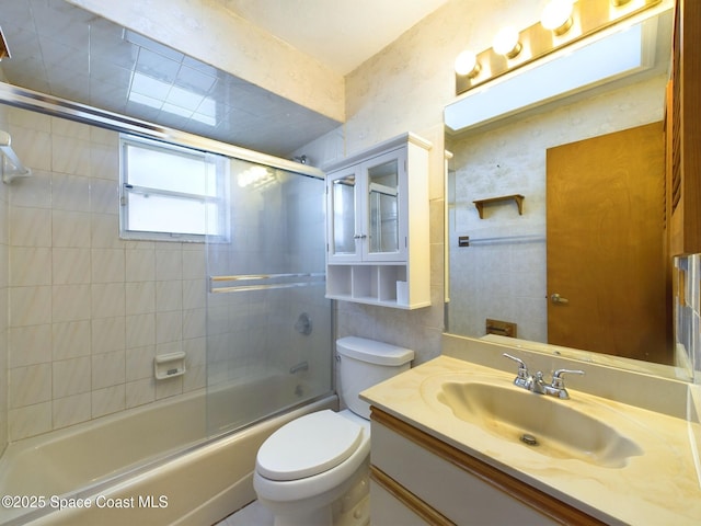 full bathroom featuring vanity, enclosed tub / shower combo, and toilet