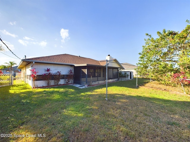 rear view of house featuring a yard and a sunroom