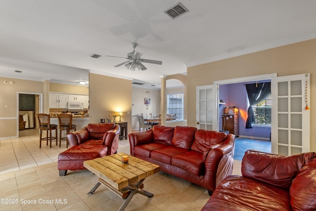 tiled living room with ceiling fan, a textured ceiling, and ornamental molding