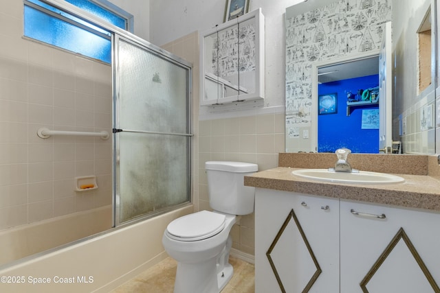 full bathroom featuring bath / shower combo with glass door, tile walls, toilet, and vanity