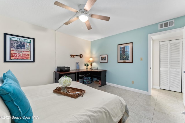 bedroom featuring ceiling fan, a textured ceiling, light tile patterned floors, and a closet