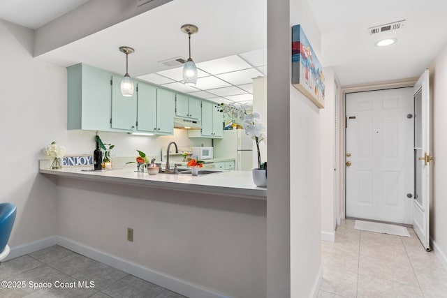 kitchen with white appliances, sink, kitchen peninsula, green cabinetry, and light tile patterned flooring