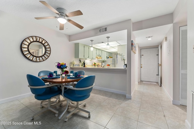 dining area featuring ceiling fan, light tile patterned flooring, and a textured ceiling