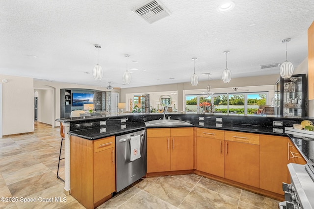 kitchen with decorative light fixtures, dishwasher, sink, a kitchen breakfast bar, and dark stone counters