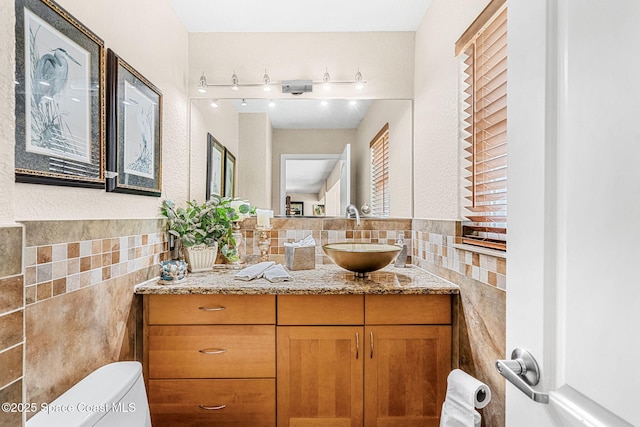 bathroom with tile walls, vanity, and toilet