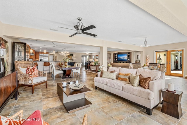 living room with ceiling fan with notable chandelier, a wealth of natural light, and a textured ceiling