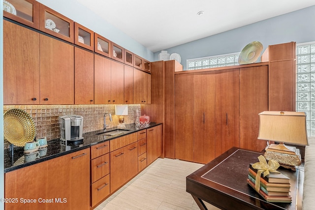 kitchen featuring a healthy amount of sunlight, sink, dark stone countertops, and decorative backsplash