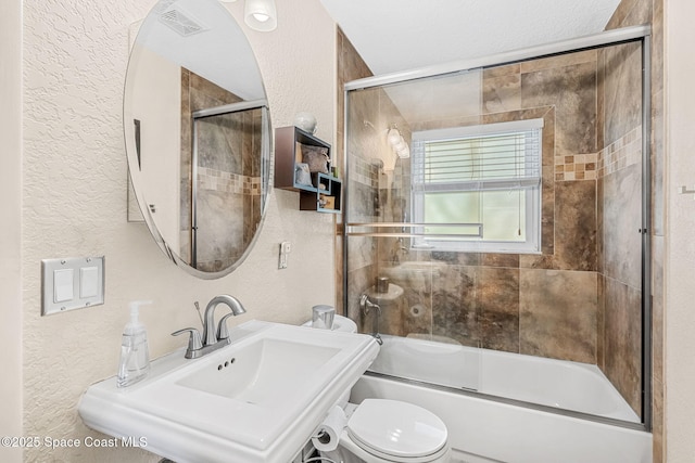 full bathroom featuring sink, shower / bath combination with glass door, and toilet