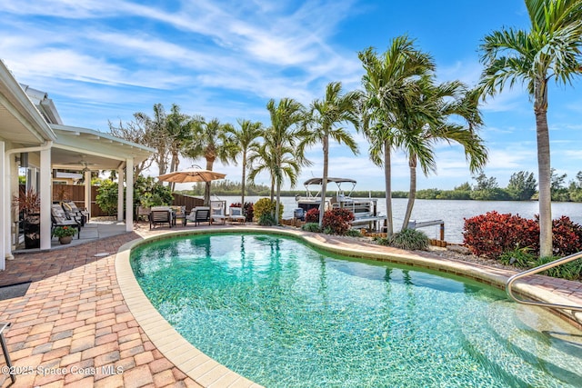 view of pool featuring a water view, a dock, and a patio area