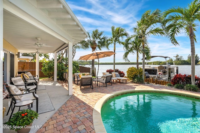 view of swimming pool with an outdoor living space, a patio, a water view, and ceiling fan