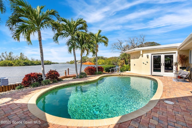 view of swimming pool with a patio, french doors, and a water view