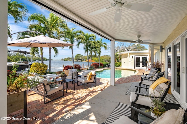 view of pool with ceiling fan, a water view, an outdoor living space, a patio area, and french doors