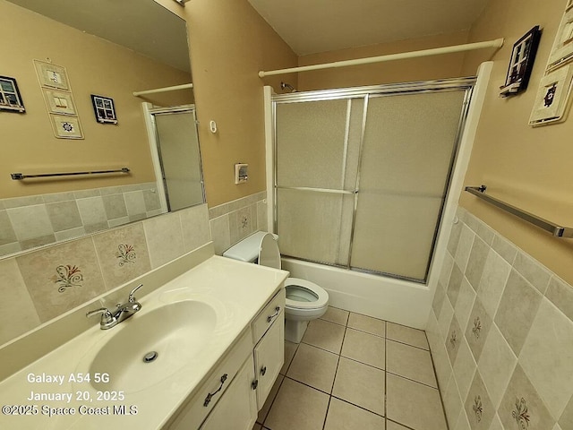 full bathroom with enclosed tub / shower combo, toilet, tile patterned flooring, and tile walls