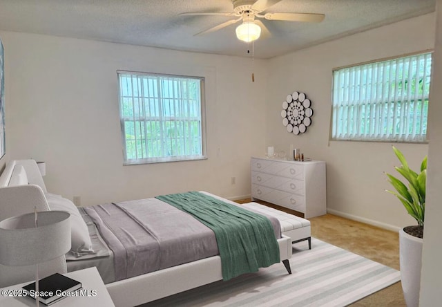 bedroom featuring ceiling fan, carpet, multiple windows, and a textured ceiling