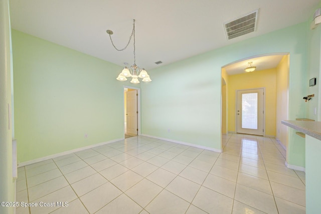 spare room with arched walkways, light tile patterned floors, visible vents, baseboards, and an inviting chandelier