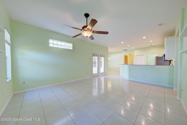 unfurnished room with light tile patterned floors, baseboards, arched walkways, a ceiling fan, and recessed lighting