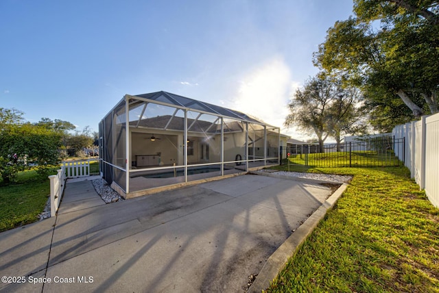 back of property featuring a lanai, a fenced in pool, a patio area, and a lawn