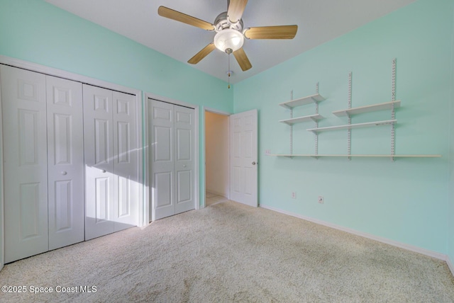 unfurnished bedroom featuring two closets, ceiling fan, and carpet