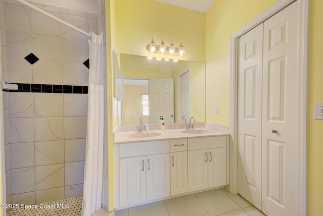 bathroom featuring double vanity, tiled shower, tile patterned flooring, and a sink