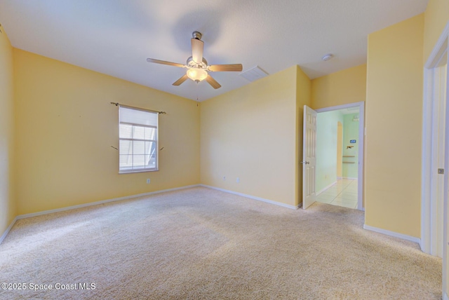 spare room with a ceiling fan, light carpet, visible vents, and baseboards