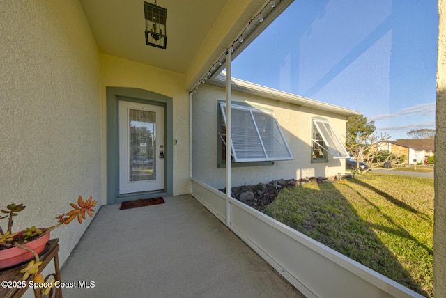 property entrance with a lawn and stucco siding