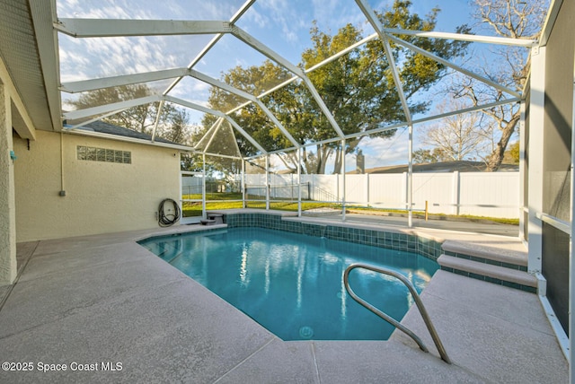 view of pool with glass enclosure, a patio area, a fenced backyard, and a fenced in pool