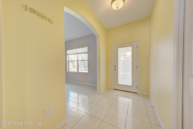 foyer with light tile patterned floors, baseboards, and arched walkways