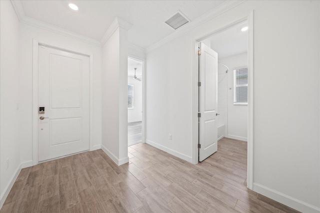 foyer entrance with ornamental molding and light hardwood / wood-style floors