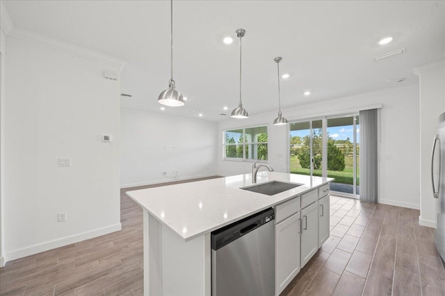 kitchen featuring pendant lighting, white cabinetry, stainless steel appliances, sink, and a kitchen island with sink