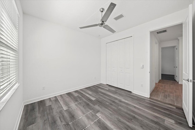 unfurnished bedroom with ceiling fan, dark hardwood / wood-style floors, and a closet