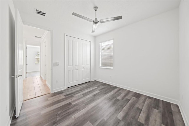 unfurnished bedroom with ceiling fan, wood-type flooring, and a closet