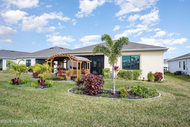 rear view of house featuring a sunroom and a lawn