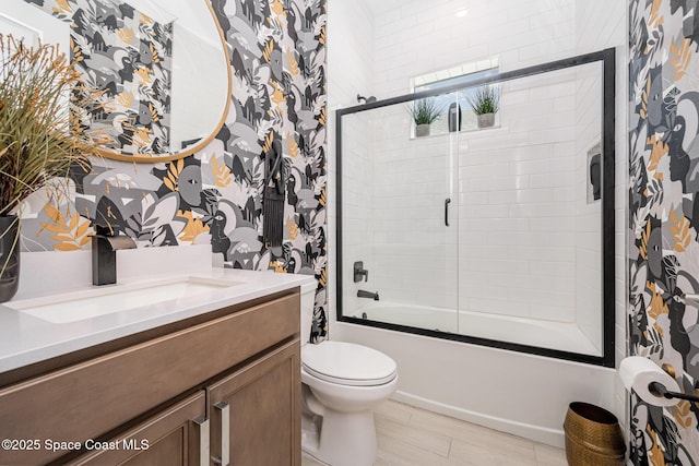 full bathroom with vanity, bath / shower combo with glass door, and toilet