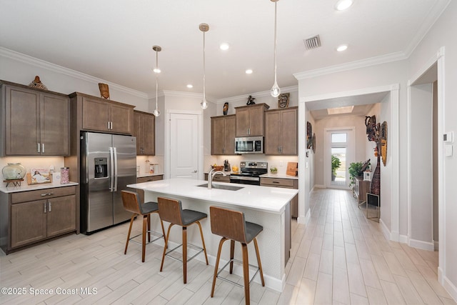 kitchen featuring sink, a breakfast bar area, a center island with sink, appliances with stainless steel finishes, and pendant lighting