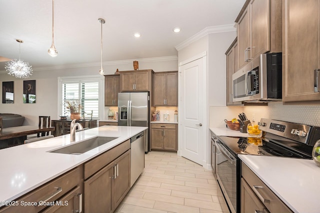 kitchen featuring sink, appliances with stainless steel finishes, ornamental molding, decorative backsplash, and decorative light fixtures