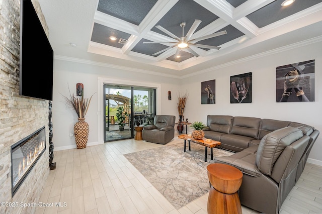 living room featuring coffered ceiling, a stone fireplace, ornamental molding, and light wood-type flooring