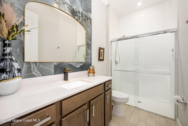 bathroom with vanity, a shower with shower door, and toilet