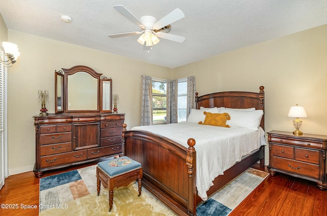 bedroom featuring a textured ceiling, ceiling fan, and dark hardwood / wood-style flooring