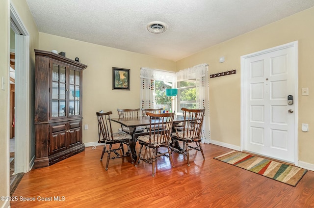 dining area with a textured ceiling and wood-type flooring