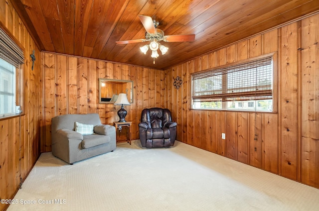 sitting room featuring carpet floors, wood ceiling, ceiling fan, and wooden walls